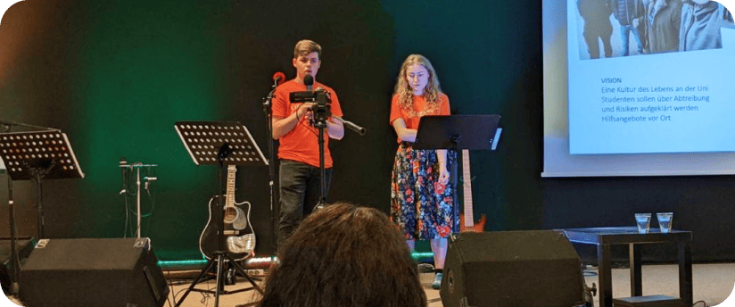 Two ProLife Europe members speaking on stage at a LifeTALK